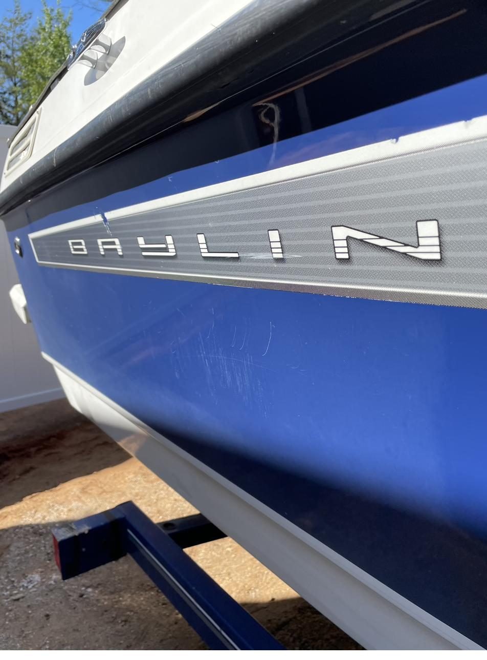 Bayliner hull with deep scratches before gelcoat restoration